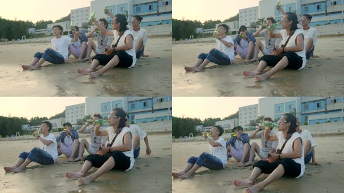 年轻的亚洲成年人坐在海滩上放松, 喝啤酒敬酒.