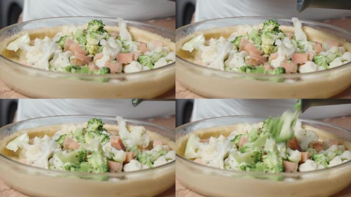 这个女人慢慢地把五颜六色的卷心菜、韭菜和三文鱼片做成的馅料铺在蔬菜派的面团上。