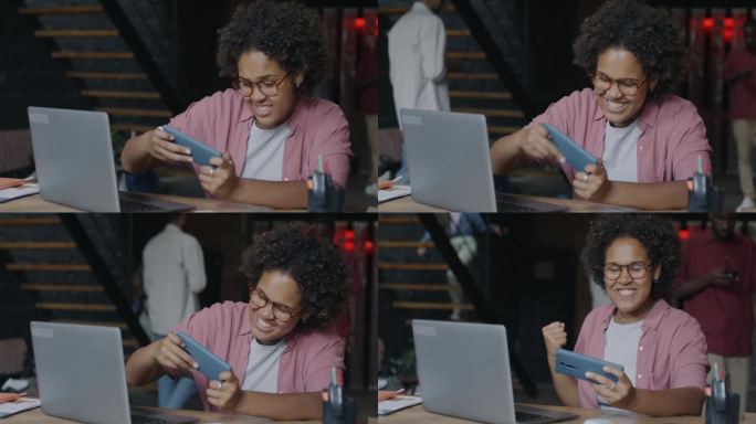 无忧无虑的非洲裔美国女商人在办公室用智能手机玩在线视频游戏