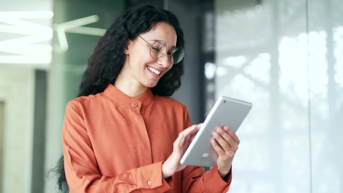 关闭了。在现代办公场所，微笑的女员工正在使用平板电脑。