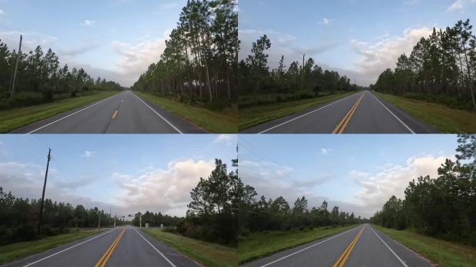 黎明时分，司机在空旷的道路上穿过松林，穿过铁路道口，蓝天上飘着远处的云