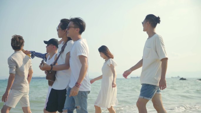 一群年轻的亚洲成年人男人和女人有乐趣步行在海滩上唱歌，后视镜。