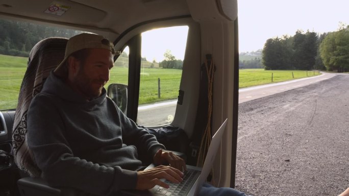 坐在舒适的面包车里用笔记本电脑工作的数字游民