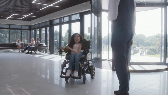坐轮椅的妇女来到诊所接待处，与行政人员交谈