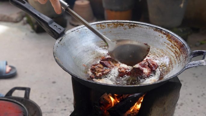 煎亚洲菜，用旧锅在木炭烤架上煎鸡内脏。