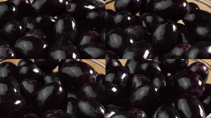 一串串新鲜的黑色葡萄旋转着作为背景。葡萄特写，概念酿酒，葡萄酒生产，葡萄品种