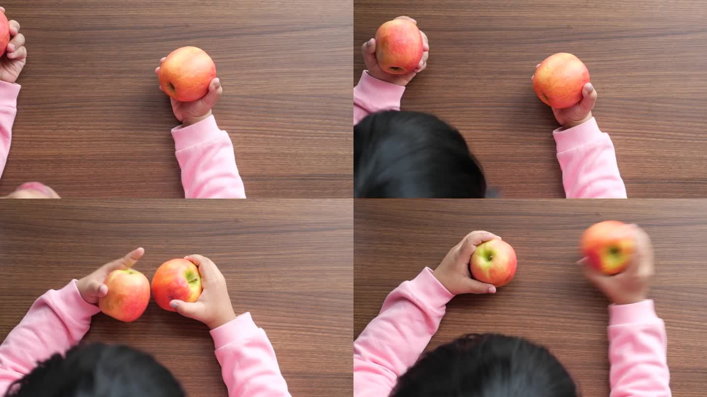 小孩用手在桌上摘苹果