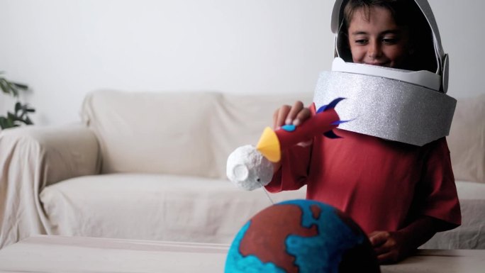 宇航员孩子在家玩头盔玩具和精巧的火箭-孩子的想象力，月球太空旅行的概念