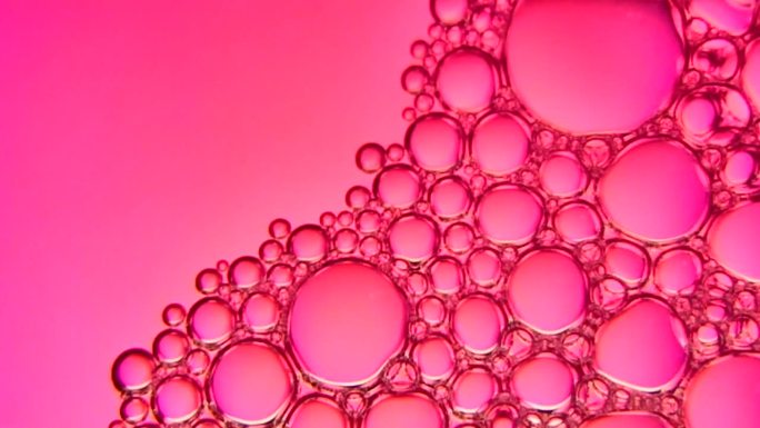 在粉红色的光背景下，肥皂泡团在运动