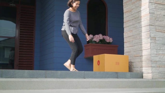 一名妇女走到自家门前，从掉在地上的邮递员手中接过包裹。