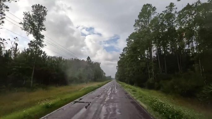 司机沿着崎岖的道路穿过森林农田和道路上的雨水水坑