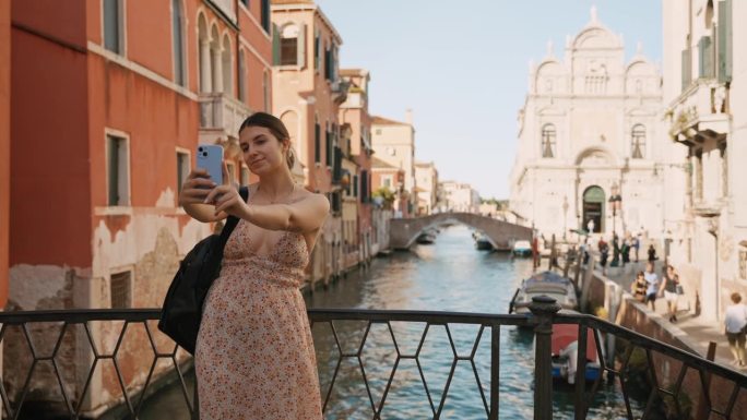 暑假期间，一名年轻女子在威尼斯运河上的一座桥上微笑自拍