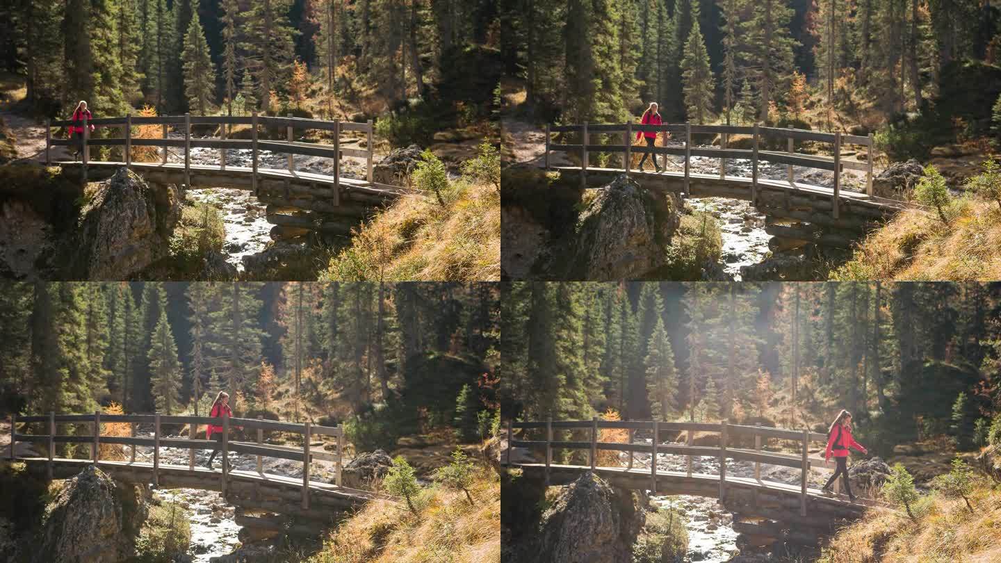 在一个阳光明媚的秋日里，一个女人走过一座木桥