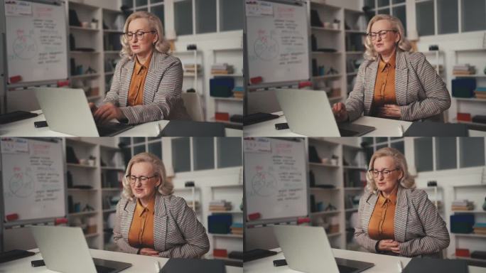 50多岁的办公室女经理在使用笔记本电脑时感到腹部疼痛