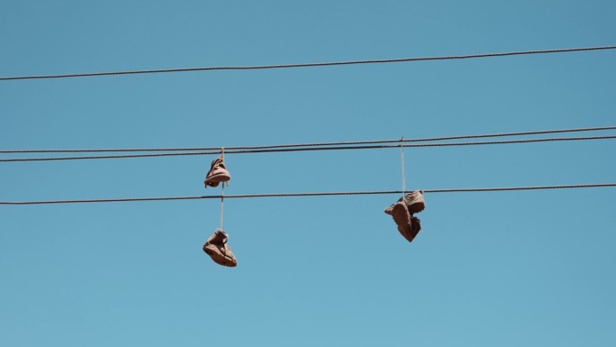 广角镜头，旧运动鞋系着鞋带悬在铁丝上。