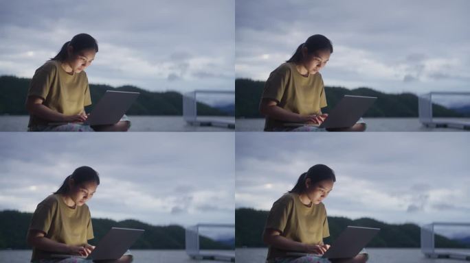 在湖边码头用笔记本电脑工作的女人