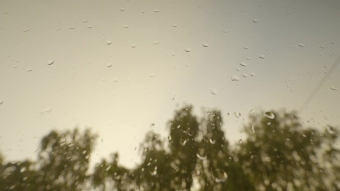 面对天空，雨滴落在玻璃窗表面，手持下降