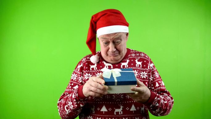 老人戴着圣诞帽，穿着圣诞毛衣，打开礼盒，很高兴。