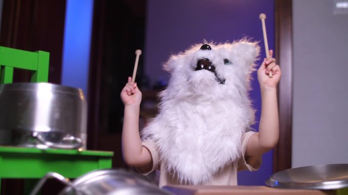 一个孩子戴着万圣节的狼面具在家里玩架子鼓和摇滚乐队