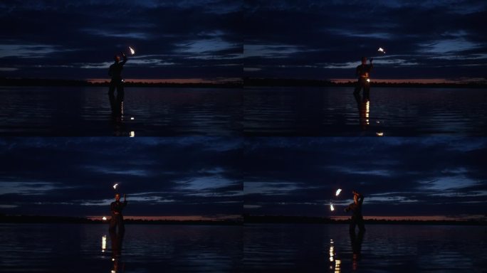 女人在夜晚玩弄燃烧的火把的剪影，女人站在河里玩火