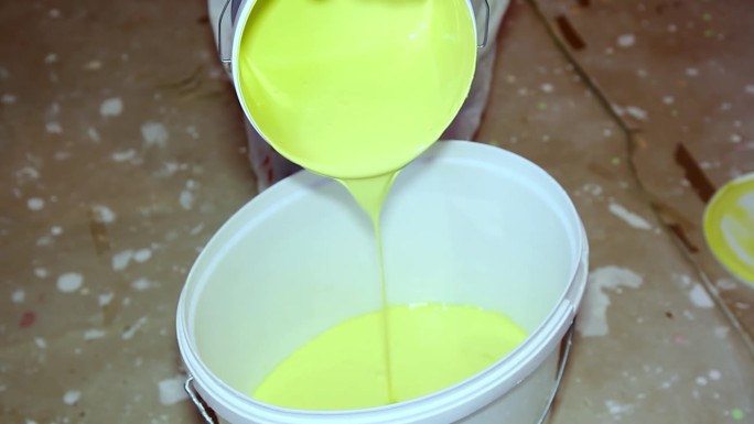 油漆匠在桶里倒黄色油漆