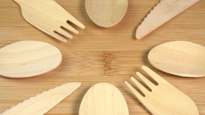 木制环保一次性餐具旋转。砧板上堆放着一堆木勺、刀叉。厨房、餐厅一次性生态餐具