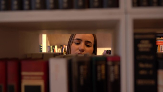 年轻女子在图书馆的展柜上看书
