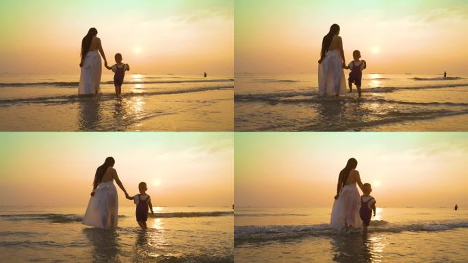 傍晚妈妈带着儿子沙滩上散步温馨夕阳下母子