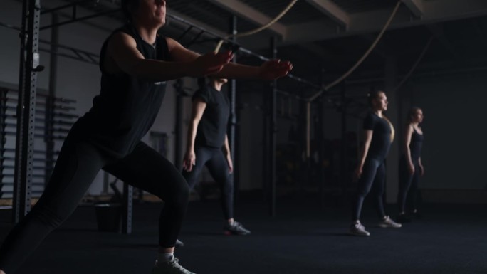 穿着运动服的女性在健身房做深蹲，在健身俱乐部训练，以保持良好的体型和健康