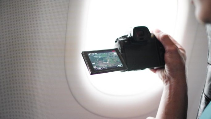 一位旅行的乘客在飞机上透过窗户拍照。