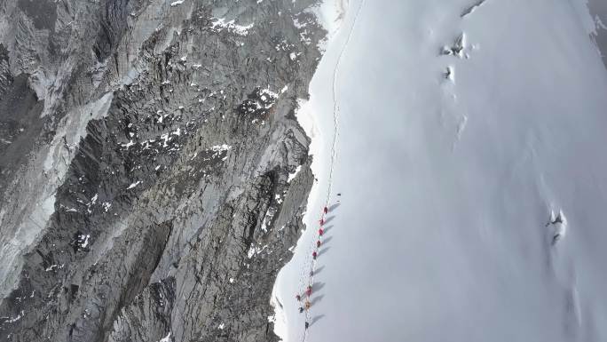 航拍攀登贡嘎山卫峰乌库楚雪山上的登山者