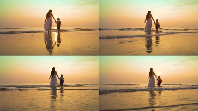 温馨母子大手牵小手走在沙滩上散步沐浴阳光