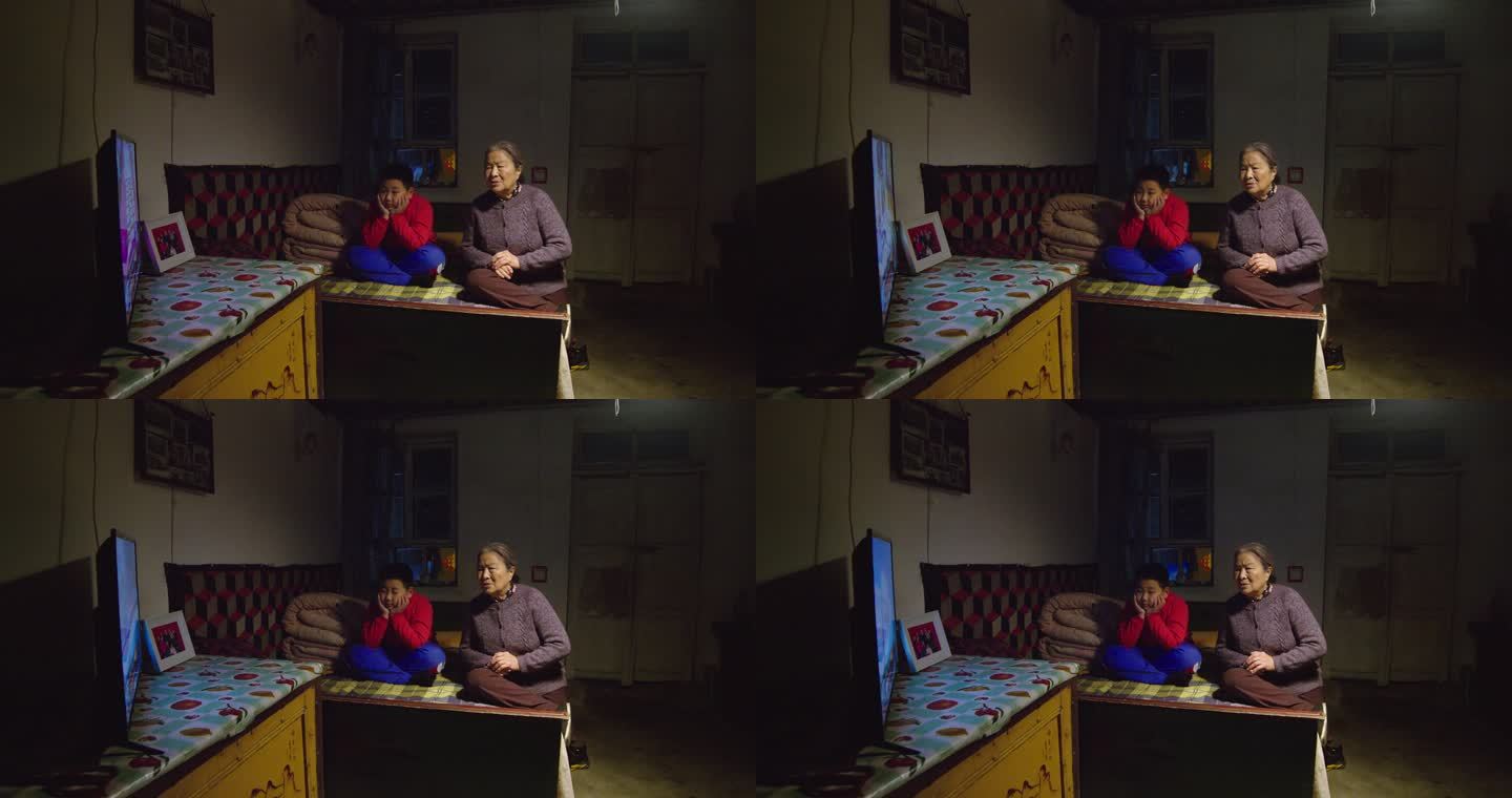 老太太和孙子坐在床上一起看电视
