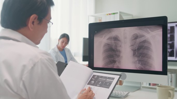 成年亚洲男医生在医院的电脑屏幕上检查病人的肺部x线图像。医疗保健。