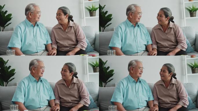 幸福的亚洲老年夫妇坐在家里的沙发上聊天。