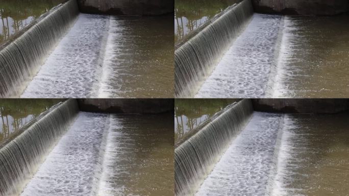 背景图:水流穿过混凝土屏障溢流坝的表面。