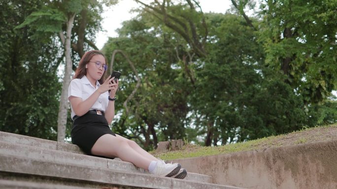 十几岁的学生女孩放松地用智能手机听歌