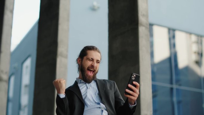 在办公室外使用智能手机的商人，脸上洋溢着快乐的情绪。