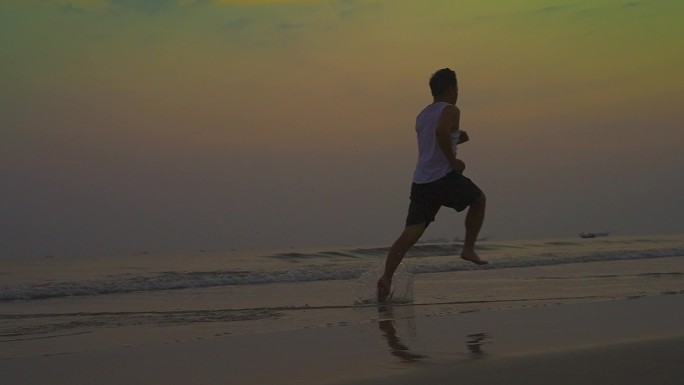 清晨青年沙滩上奔跑男人海边光脚跑步追光者