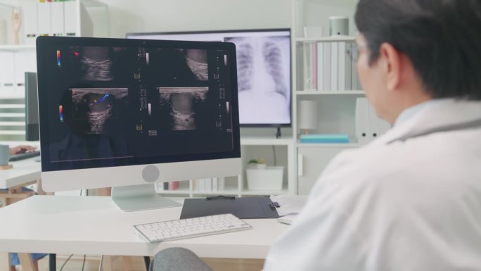 成年亚洲男医生在医院电脑屏幕上检查病人的x光图像。医疗保健。