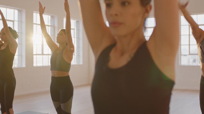 瑜伽班的美女们在健身房里练习祈祷姿势，享受健康的生活方式，在日出时锻炼身体