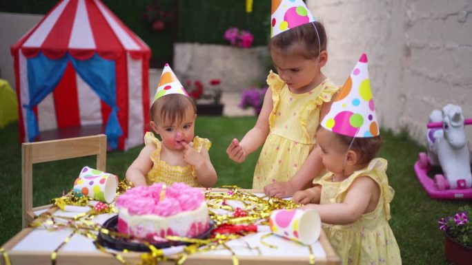 一对双胞胎姐妹和一个姐姐一起庆祝她们的一岁生日