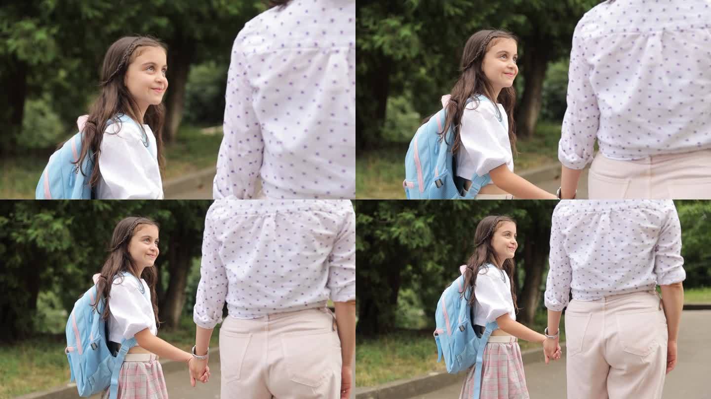 一个快乐的女孩背着书包上学，牵着妈妈的手。在学校学习