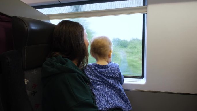 母亲带着孩子在火车上望向窗外