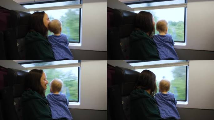 母亲带着孩子在火车上望向窗外