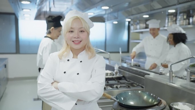 微笑的中国女厨师代表他们的烹饪团队，支持团队团结，专业烹饪团队在酒店餐厅厨房准备食物时快乐的时刻