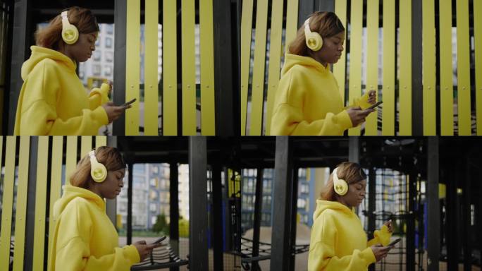 漂亮的非裔美国年轻女子带着无线耳机和智能手机走在城市里