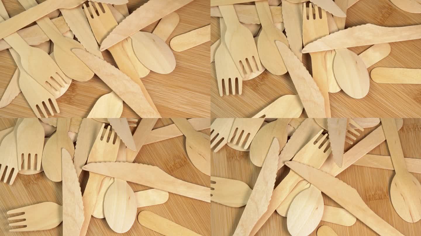 木质环保一次性餐具在木质餐桌上旋转。砧板上堆放着一堆木勺、刀叉。厨房、餐厅一次性生态餐具