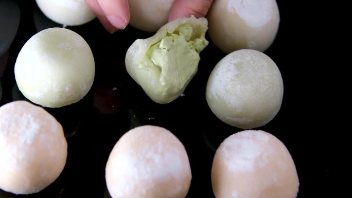 麻糬冰淇淋咬一口甜点，然后把它放回一个带有绿茶味的黑色盘子里，这是一种受欢迎的亚洲美食