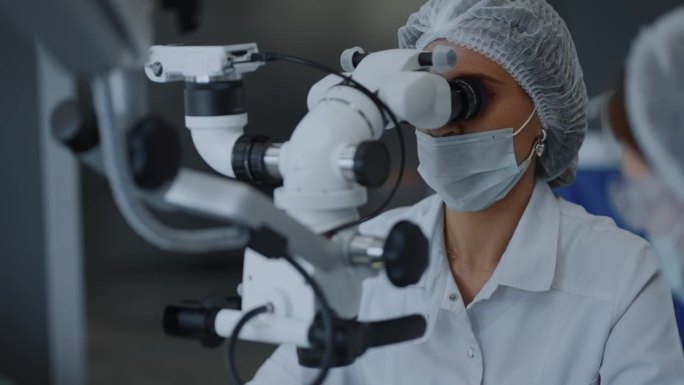 女外科医生在内窥镜手术中注视着操作显微镜